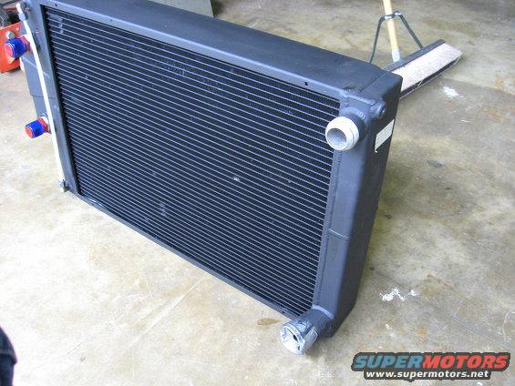 Black radiator with blue and red fittings on the left side, viewed from a 3/4 front angle