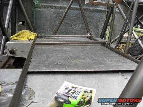 Interior of a custom off-road vehicle with a yellow rag on a metal box, and a photo of a green buggy on the floor