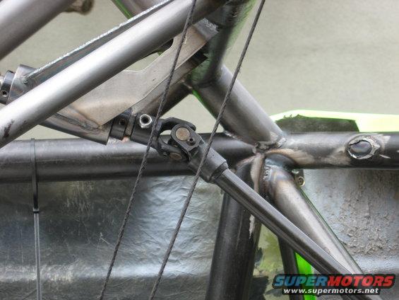 Close-up of a custom off-road vehicle's metal frame and driveshaft