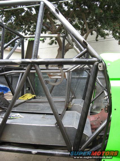 Custom roll cage structure with metal fuel tanks and a yellow rag inside a green vehicle