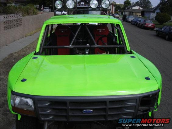 Lime green custom off-road truck with roll cage and racing seats, front view