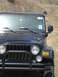 2008 International School Bus - A dark blue Jeep Wrangler is shown from the front, with a bull bar and dusty windshield, while an ATV is visible in the background on a hil…