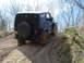 2008 International School Bus - A black Jeep Wrangler navigates a muddy, off-road trail, kicking up dirt as it ascends the incline.