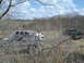 2008 International School Bus - Two pickup trucks are parked in a dry, brush-filled field under a partly cloudy sky.