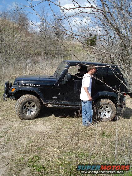 Black Jeep Wrangler Rubicon parked on a dirt path with a person standing next to it