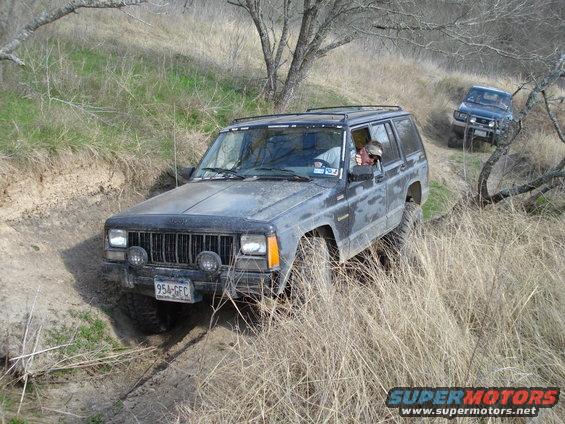 Jeep Cherokee XJ driving on a dirt trail with another Jeep behind it