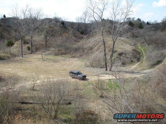 Dark SUV on dirt road in hilly, dry landscape