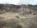 2008 International School Bus - SUV navigates a dirt path in a desolate, treeless environment.