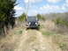 2008 International School Bus - A black Jeep Wrangler drives down a dirt path through a wooded area on a cloudy day.
