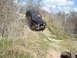 2008 International School Bus - Jeep Wrangler navigating a steep, dry dirt trail with sparse vegetation.