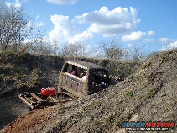 Pickup truck stuck in a dirt ditch with a red gas can in the back