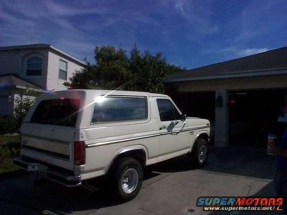 White SUV parked in driveway, rear quarter view. Chrome trim, aftermarket wheels
