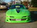 1994 Ford Probe - A lime green sports car with a custom body kit is parked in front of a house, with a 'For Sale' sign in the window.
