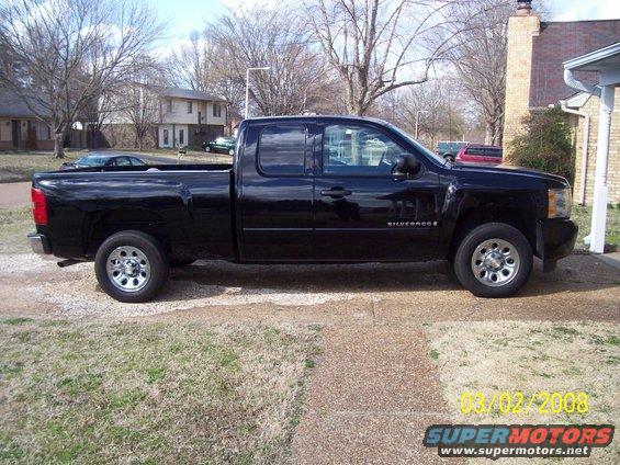 Black Chevrolet Silverado pickup truck, side view, parked in driveway