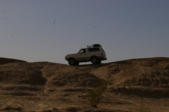 White 1986 Ford Bronco on dirt hill with roof rack