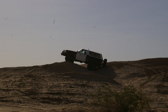 SUV climbing sand dune, side view