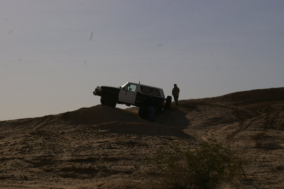 Two-tone Ford Bronco on a dirt hill with a person standing nearby