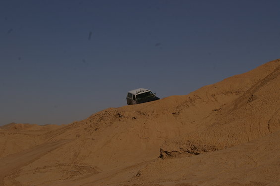 White top SUV driving on a sand dune