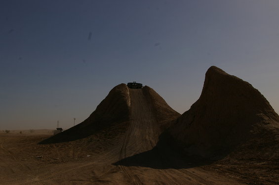 SUV driving up a steep dirt hill with a clear blue sky