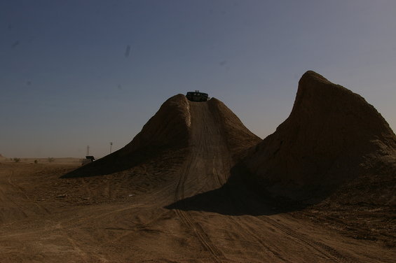 Dark SUV cresting a dirt hill under a clear blue sky