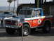 1996 Ford Bronco - This modified Ford Bronco, likely from the 1970s, is parked in a lot with other vehicles and palm trees.