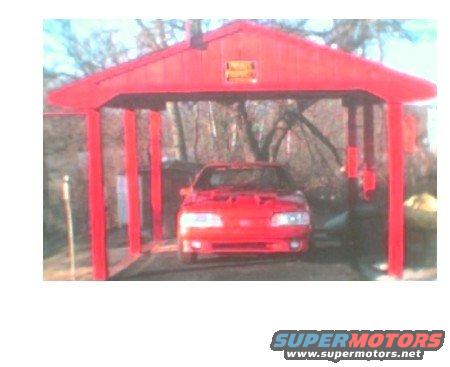 Red car parked under a red shelter structure. The car's hood is up
