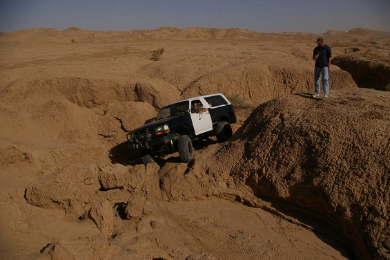 Black and white Ford Bronco driving off-road in desert terrain