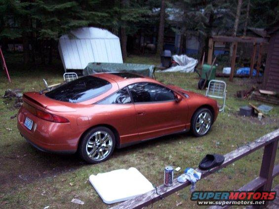 1995 Mitsubishi Eclipse coupe with a sunroof, parked in a grassy yard with trees and a shed