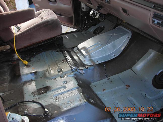 interior floor of a vehicle with seats removed, showing exposed metal and some tools