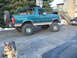 1996 Ford Bronco - A lifted green Ford Bronco is parked outside a building with a dog in the foreground.