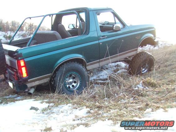 Green 1996 Ford Bronco with lifted suspension and off-road tires driving on snowy terrain