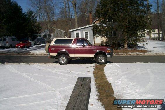 Maroon and tan 1993 Ford Bronco side view in snow