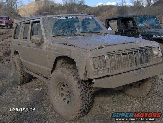 Mud-covered Jeep Cherokee, 3/4 front view, with Texas A&M sticker on windshield