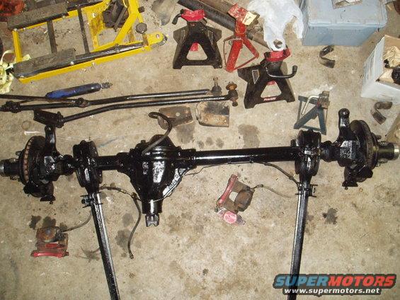 Black front axle assembly with brake components and steering linkage