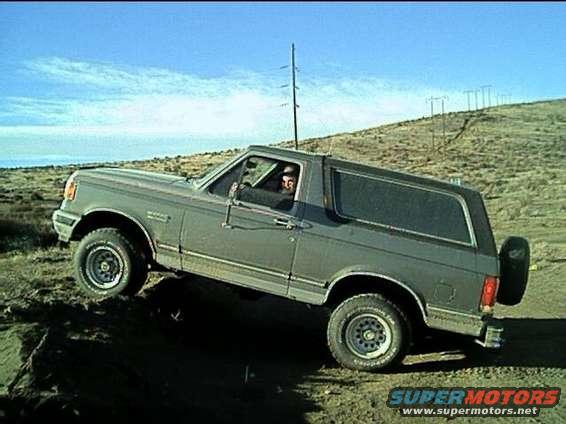 Gray Ford Bronco driving off-road, angled from the front-quarter view