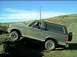 1989 Ford Bronco - A gray Ford Bronco navigates a dirt hill, its off-road capabilities.