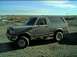 1989 Ford Bronco - This gray Ford Bronco, likely a 1987 model, is parked on a gravel lot under a partly cloudy sky.