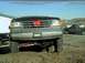 1989 Ford Bronco - Front view of a lifted Ford Bronco with a red bow on the grille; a pickup truck is visible in the background.