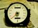 1976 Ford Ranchero - Speedometer gauge with white face and black housing, resting on newspapers.