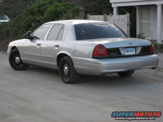 Silver 2003 Ford Crown Victoria parked on a dirt road near a house
