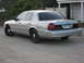 2003 Ford Crown Victoria - This silver 2003 Ford Crown Victoria is seen from the rear quarter angle on a dirt road.