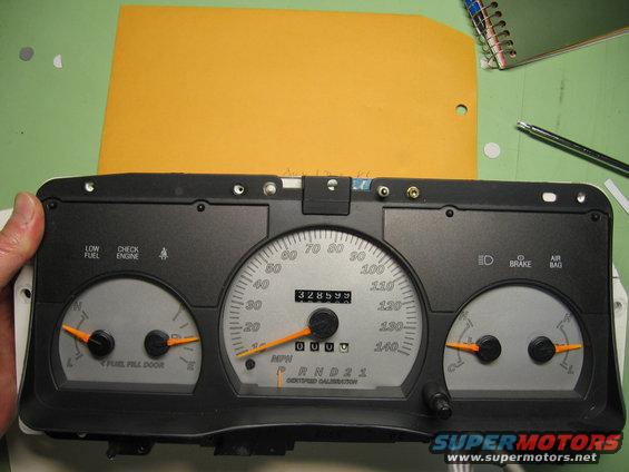 Car dashboard instrument cluster with speedometer, fuel gauge, and temperature gauge. Odometer shows 328599