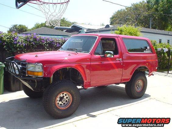 Red 1993 Ford Bronco with aftermarket bumper and lifted suspension