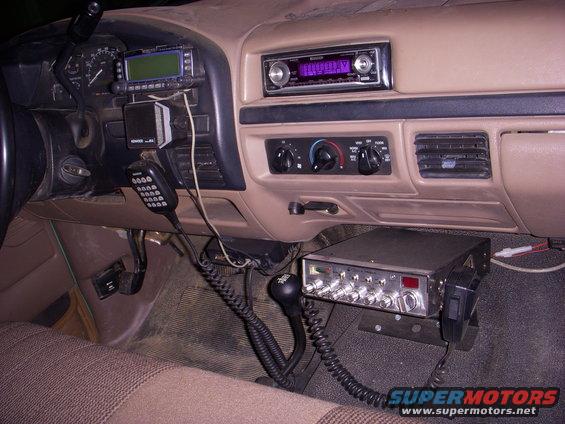 Dashboard of a truck with a CB radio mounted below the dash, a Kenwood radio on the dash, and an aftermarket stereo above the vents