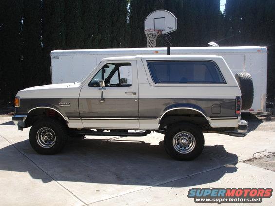 Two-tone white and grey Ford Bronco parked on a driveway, side view
