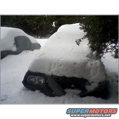 Two cars covered in thick snow, only headlights of one are visible