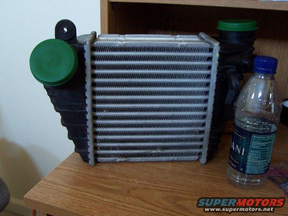 Intercooler with green caps and a water bottle on a wooden surface