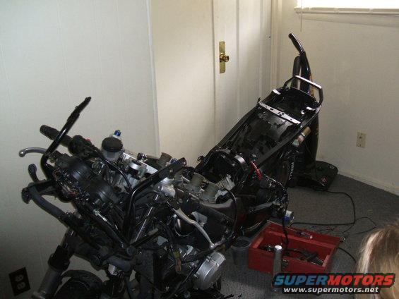 Disassembled motorcycle in a room, with a red toolbox nearby