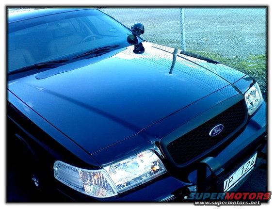 Front view of a dark blue Ford Crown Victoria with a black grille and a push bar. License plate reads 'JP 124'