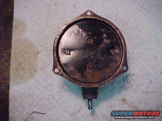 Close-up of a rusty, round, black car part with a shaft extending from the bottom. Text at the bottom reads SUPERMOTORS